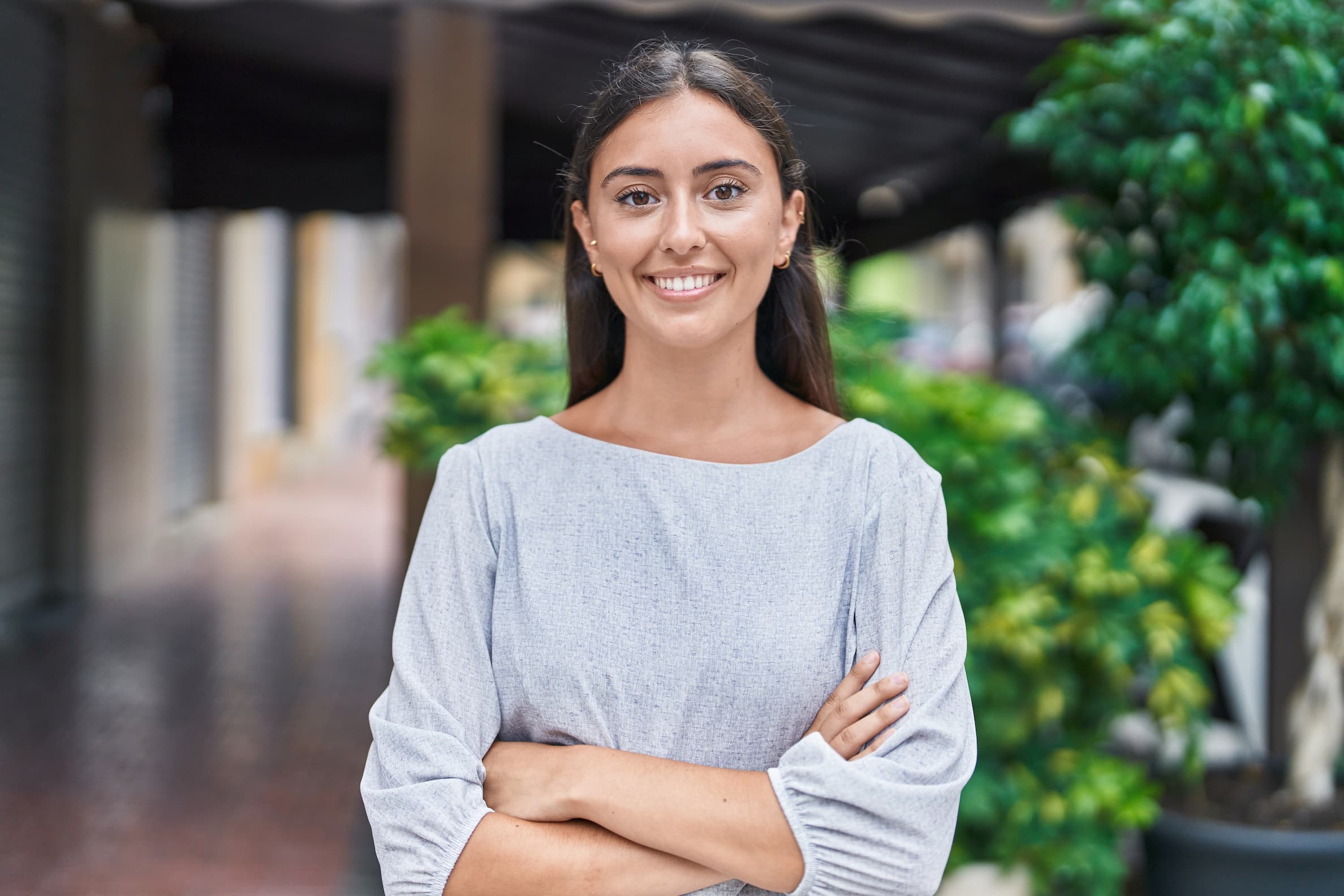 Young beautiful hispanic woman standing with arms crossed gesture in the street